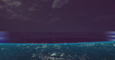 Calm waters stretch across the horizon under a dark sky illuminated by scattered clouds. A serene...