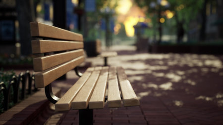 Golden light filters through the trees in an urban park, casting shadows on the wooden bench. Leaves rustle gently as soft hues of twilight envelop the tranquil scene, inviting quiet reflection.の写真素材