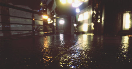 Raindrops create a glossy surface on the street, mirroring the vibrant city lights. A person walks...