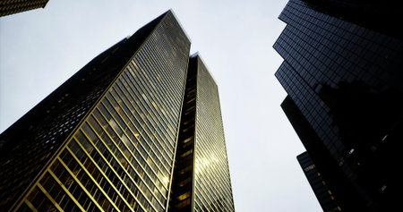 Tall skyscrapers loom overhead, their glass faÃ§ades glimmering with reflections as clouds cover the sky. The city feels alive with activity below, hinting at urban vibrancy.の写真素材