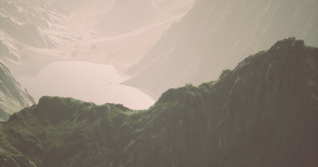 Dramatic mountain terrain showcases lush greenery and a tranquil lake below, enveloped in soft morning light. The natural beauty invites exploration and admiration of the surroundings.の写真素材