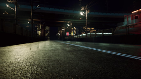 An empty street shines under city lights at night. The wet pavement reflects vibrant colors from...