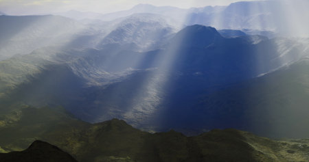 Breathtaking view of a mountain range during early morning. Soft rays of sunlight break through...