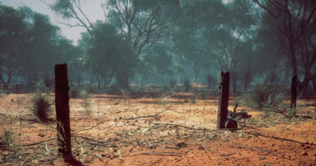 In a rugged terrain, weathered posts stand as remnants in a dusty landscape, surrounded by sparse...