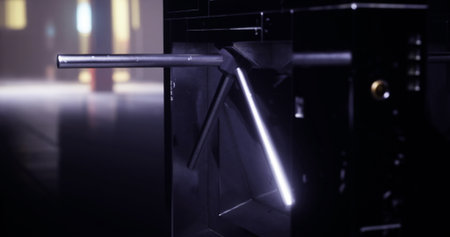 Metal turnstile with illuminated features functions in a contemporary urban environment at night....