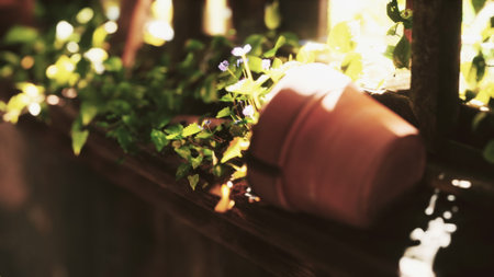 A small clay pot tipped over spills fresh soil and blooming flowers beside lush green vines. Sunlight filters through, creating a warm, inviting atmosphere in this peaceful garden setting.の写真素材