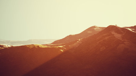 Golden sunlight filters across the rugged mountain tops, highlighting their majestic silhouettes....