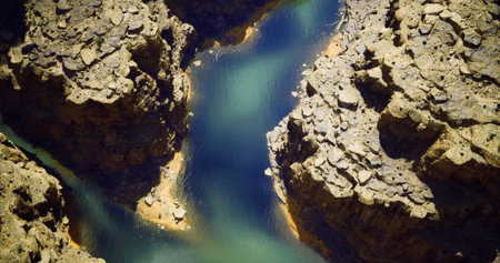 A breathtaking view showcases a winding river cutting through dramatic rock formations under clear...