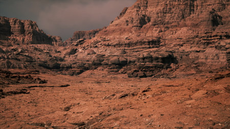 This vast desert landscape features towering rugged cliffs and dry earth, illuminated by the soft light of twilight. The tranquil yet dramatic scenery captures the essence of a remote wilderness.の写真素材