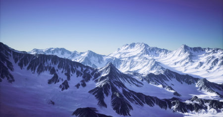 A stunning view of snow covered mountains stretches across the horizon under a bright blue sky. The...