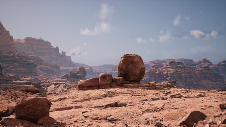 Vast desert landscape showcases towering rock formations bathed in sunlight. The dry terrain features layered cliffs and scattered stones, creating a serene and grand natural scene.の写真素材