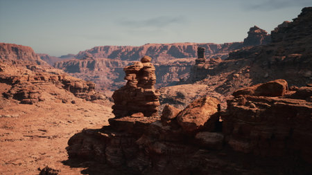A breathtaking landscape showcases towering red rock formations framed by rugged canyon walls, illuminated by the bright midday sun in a remote desert location.の写真素材