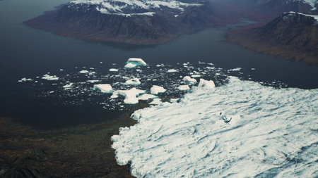 Majestic icebergs drift across a tranquil Arctic bay, surrounded by dramatic mountain ranges. The...