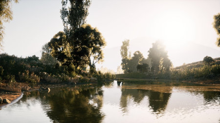 A peaceful early morning by the lake reflects the soft light of dawn, with trees lining the shore and gentle ripples on the water creating a calming atmosphere.の写真素材
