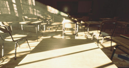 Sunlight filters through large windows in a classroom, casting shadows across empty desks and chairs. The atmosphere is calm, inviting reflection in a peaceful space for learning.の写真素材