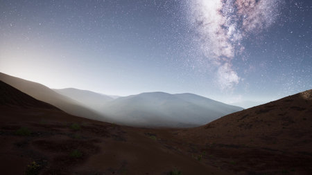 Under a clear night sky, starry brilliance illuminates the mountain range. A soft glow from the horizon enhances the tranquil atmosphere. Natures beauty captivates in this peaceful setting.の写真素材