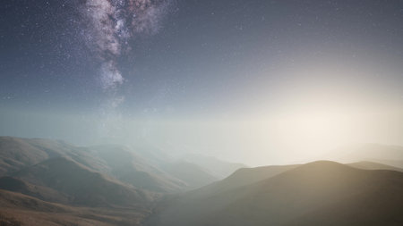 Breathtaking mountains extend under a clear, starry sky filled with the milky way. Soft light glows on the horizon, creating a serene atmosphere during a quiet night in nature.の写真素材