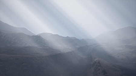 Layers of mountain ridges emerge from a blanket of mist, illuminated by gentle rays of light at dawn. A peaceful atmosphere envelops the serene wilderness, inviting reflection and exploration.の写真素材