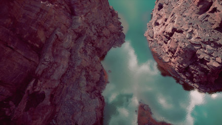 Vivid sunlight illuminates the rugged canyon walls while calm turquoise water mirrors the skys...