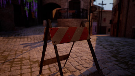 A construction barrier sits in the middle of a cobblestone street in a quaint historic town. The warm light of dusk creates a cozy atmosphere as shadows dance on the walls.の写真素材