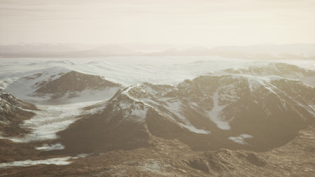 Mountain peaks stretch across the horizon, bathed in gentle sunlight. Snow covers the rugged landscape, creating a serene and peaceful atmosphere that invites exploration and wonder.の写真素材