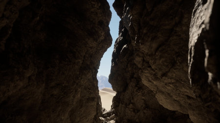 Sunlight streams through a narrow opening between towering rocks, revealing a vast sandy expanse. The journey through the rocky terrain feels adventurous and mysterious.の写真素材