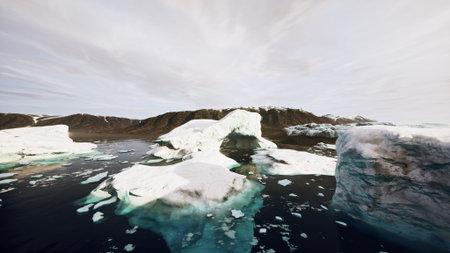 Icebergs drift gracefully in the calm Arctic waters, surrounded by rugged mountains. Soft light enhances the beauty of this pristine, untouched nature. The tranquil scene evokes peace and wonder.の写真素材