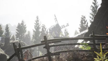 A serene village setting emerges through a veil of thick mist, featuring a traditional windmill partially obscured behind lush pine trees. The rustic fence adds charm to the peaceful atmosphere.の写真素材