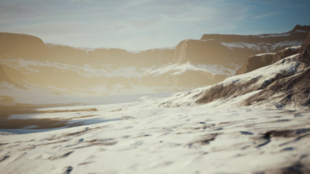 Soft sunlight bathes a vast snowy landscape at dawn, revealing towering mountains and serene valleys. The tranquil scene showcases natureâs beauty in a remote location, untouched by human presence.の写真素材