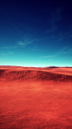 A vast red desert stretches as far as the eye can see, illuminated by a bright blue sky. The arid terrain features rolling dunes and distant mountains, creating a striking contrast.の写真素材
