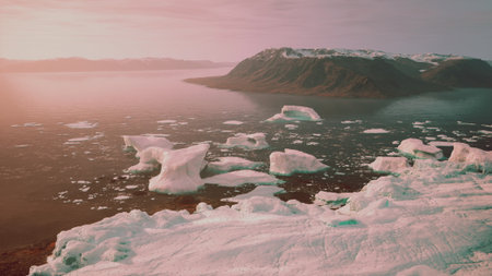 Beautiful icebergs drift serenely across calm water, reflecting the soft pink hues of dawn....