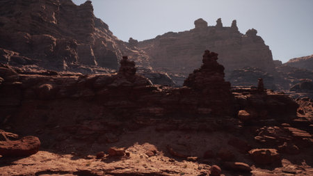 Majestic rock formations rise in the clear blue sky, illuminated by the bright midday sun. The landscape showcases the natural beauty of arid terrain, perfect for exploration.の写真素材