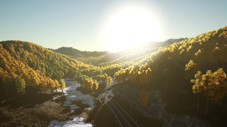Golden sunlight spills over rolling hills covered in rich autumn colors. A winding railway cuts through the serene valley, surrounded by trees and a hint of winter snow.の写真素材