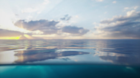 Water stretches endlessly towards the horizon where the sun sets, casting soft colors. Gentle waves create a smooth surface, adding tranquility to the beautiful sky above.の写真素材