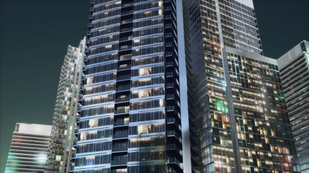 Tall buildings rise against the night sky, their windows glowing with warm lights. The urban landscape showcases a blend of sleek architecture and city life, creating a lively atmosphere.の写真素材