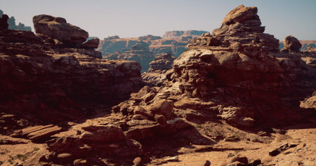 Large rock formations dominate a rugged desert landscape, showcasing unique geological patterns. The clear sky enhances the earthy tones of the rocks in this vast, arid environment.の写真素材