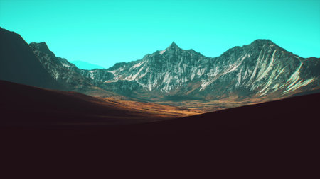 Towering mountains stretch across the horizon, showcasing rugged peaks and colorful valleys illuminated by natural sunlight beneath a clear blue sky.の写真素材