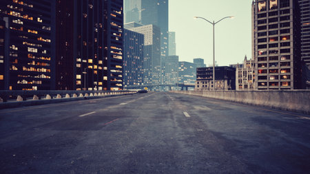 A vast highway stretches ahead, flanked by towering skyscrapers. Flickering lights hint at city life above, while the quiet road sets a tranquil yet urban mood as dusk approaches.の写真素材