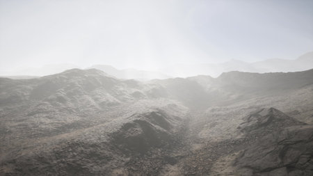 Vast rocky hills rise dramatically beneath a soft mist as dawn breaks, creating an ethereal atmosphere. Sunlight gently illuminates the rugged features, inviting adventure and exploration.の写真素材