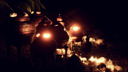 Clay pots filled with flickering candles illuminate a serene garden at night. The warm glow casts dancing shadows, creating a peaceful and magical ambiance among the greenery.の写真素材