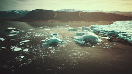 Majestic icebergs drift in calm waters as the sun sets behind snow capped mountains, creating a stunning reflection in the serene fjord landscape, showcasing natures beauty and fragility.の写真素材