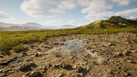 A vast landscape features scattered rocks and a small puddle reflecting the blue sky. Lush green grass sways gently in the background, creating a peaceful natural scene.の写真素材