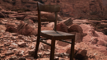 A wooden chair stands alone on rocky ground, surrounded by stunning red rocks under a clear blue sky. This unusual scene evokes feelings of solitude and reflection in natures embrace.の写真素材