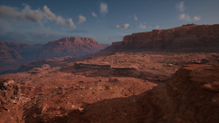Vast red rock formations stretch under a clear sky. The landscape reflects the warm hues of the setting sun, revealing textures and shadows. Natures beauty is on full display here.の写真素材