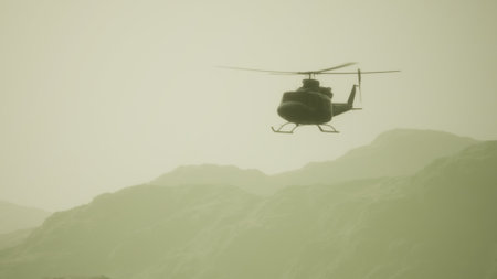 A helicopter hovers gracefully against soft mountain silhouettes. The early morning light casts a hazy glow, creating a calm, dreamy atmosphere. Natures beauty unfolds in the background.の写真素材