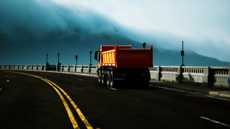 A brightly colored truck moves along a winding coastal road. Thick fog rolls in from the ocean, creating a mysterious atmosphere.の写真素材