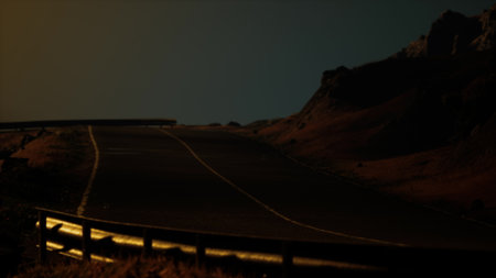 A curving road stretches through rugged mountains, illuminated softly by moonlight. The atmosphere is calm and mysterious, capturing the beauty of nighttime travel in nature.の写真素材