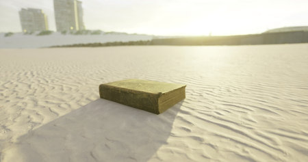 As the sun sets on a peaceful beach, an old book rests in the sand, its worn pages inviting curious minds to uncover its forgotten tales in the serene surroundings.の写真素材