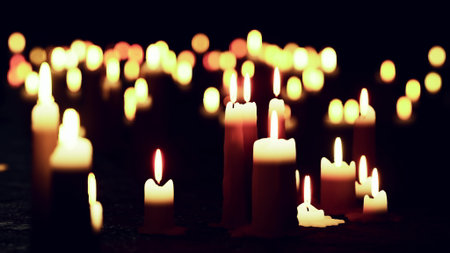 A peaceful scene features numerous candles flickering gently in the dark. Their warm, soft light creates a calming atmosphere, enhancing the tranquility of the night.の写真素材
