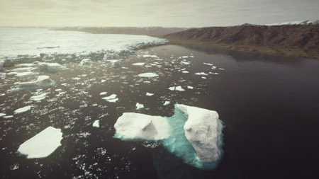 Drifting icebergs float in a quiet Arctic fjord, surrounded by rugged mountains. The gentle...